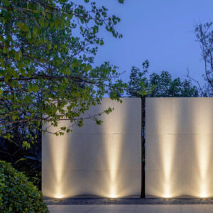Architectural wall illuminated from the bottom using LED uplighters to create soft vertical lighting effect